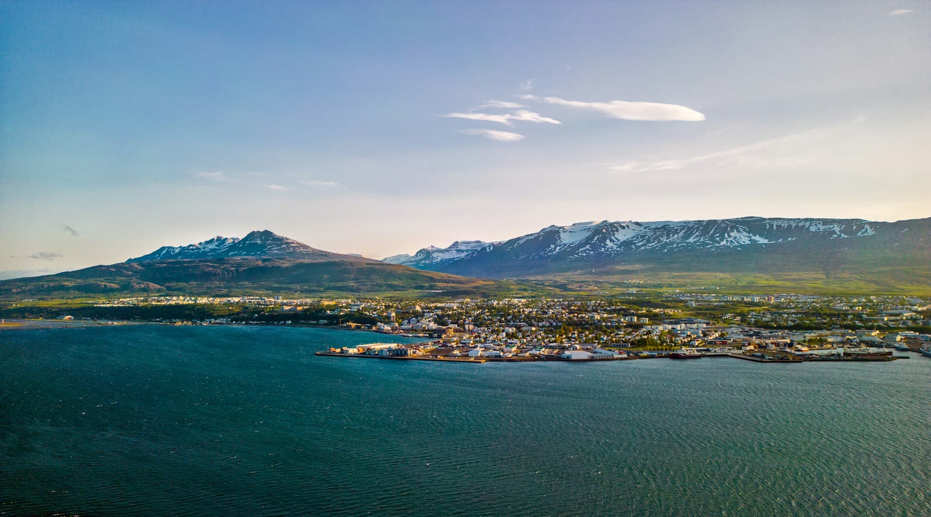 Aerial view of Akureyri town along Eyjafjörður fjord below snow-capped mountains