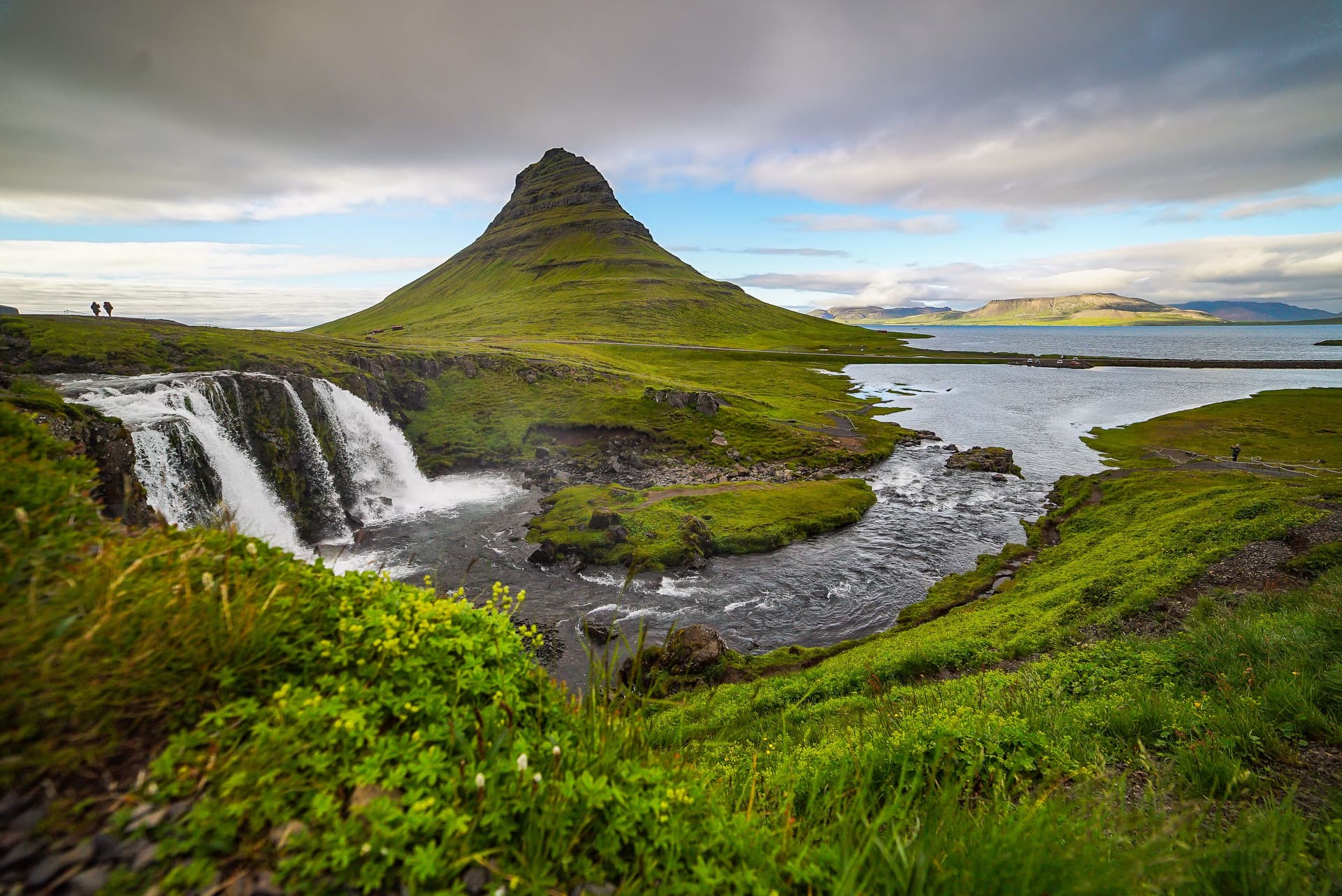 Kirkjufell mountain rising above a fjord, seen across the tiered Kirkjufellsfoss waterfall
